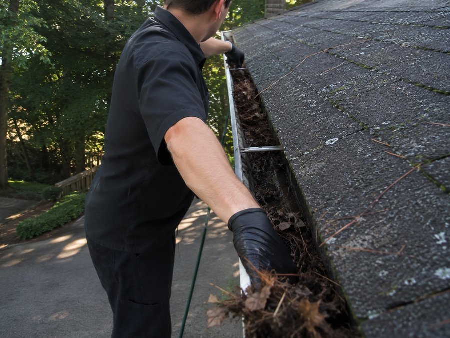 Clearing debris out of a gutter by hand